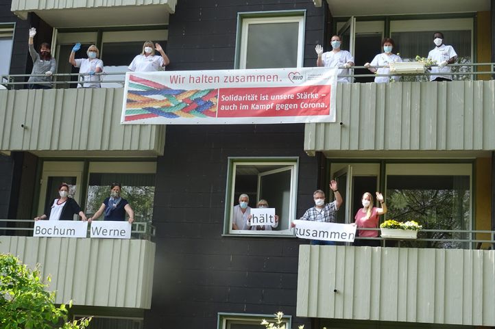 Menschen mit Bannern und Schildern winken von Balkonen runter