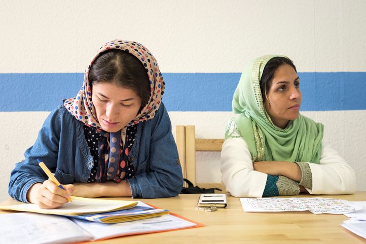 zwei Frauen in Kopftuch sitzen am Tisch und lernen