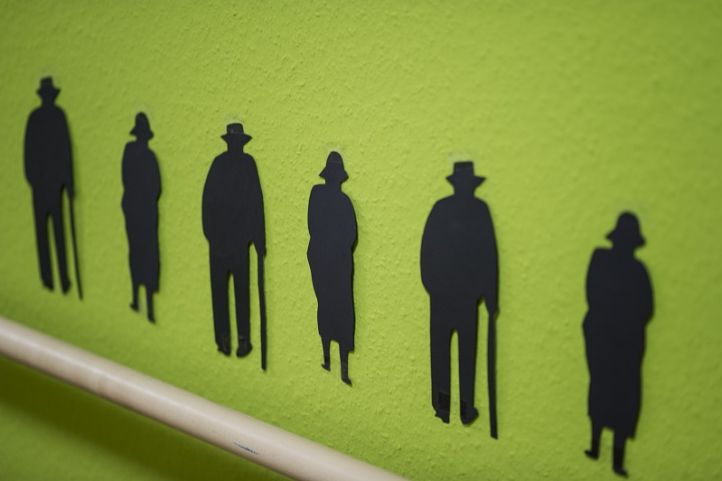 Ältere Menschen als schwarze Schablone auf grüne Wand gemalt