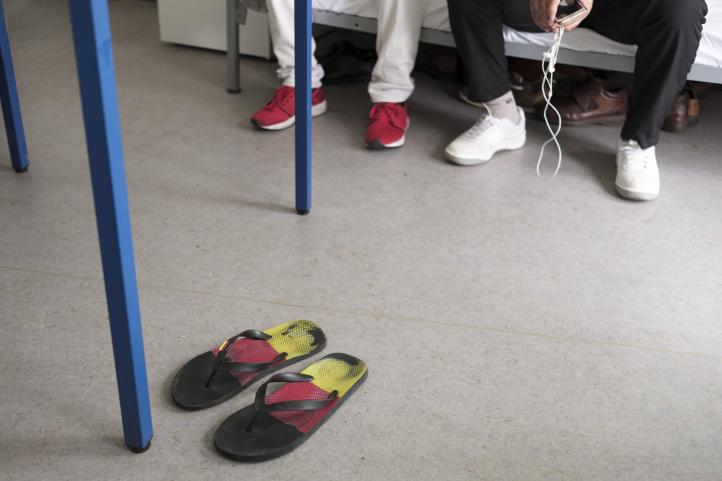 Flip Flops in den Farben der Deutschlandfahne stehen neben einem Tisch auf dem Boden