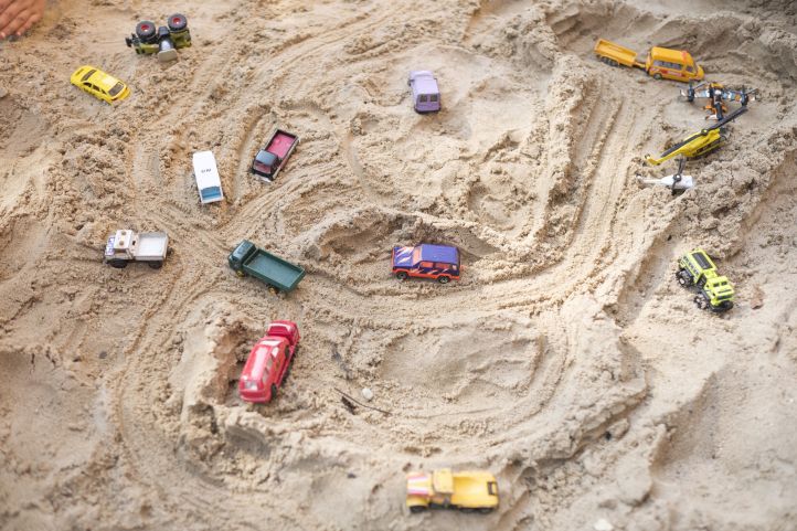 viele Spielzeug Autos liegen im Sand