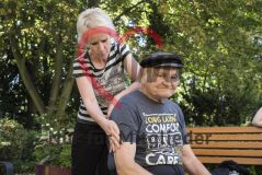 Eine Frau massiert einen alten Mann Senior auf einer Parkbank