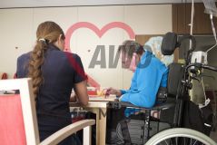 Ein alter Mann Senior in einem Rollstuhl spielt ein Motorikspiel an einem Tisch in einer Einrichtung
