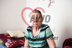 Eine alte Frau Seniorin sitzt im Bett eines Pflegeheims und blickt in die Kamera
