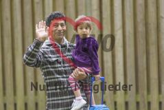 Ein Mann mit einem Kind Tochter auf dem Arm winkt in die Kamera
