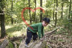 Junge im Wald, auf einem Baumstamm kletternd